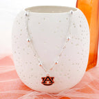 Seasons Jewelry Auburn Glitter Enamel Logo Necklace featuring beaded accents and an orange AU pendant, displayed on a white textured vase.