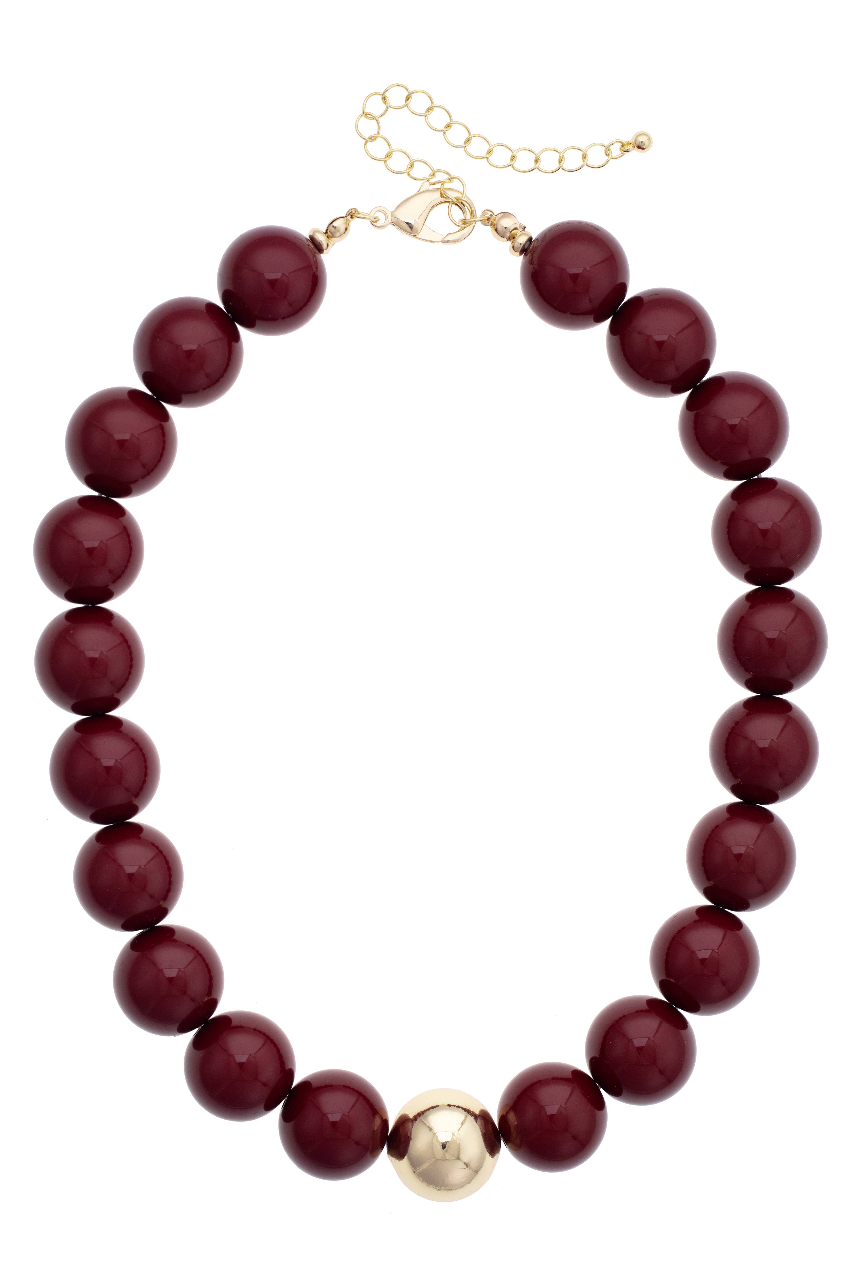 The Marjorie Game Day Beaded Necklace from Canvas Style features oversized burgundy beads accented by a single central gold bead, finished with a gold chain and clasp for adjustable length—a bold statement necklace designed to elevate any outfit.