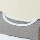 Close-up of the Shewin Khaki Color Block Exposed Seam Long Sleeve Top, highlighting its unique patchwork design in grey, white, and brown, with meticulous attention to stitching and neckline detail.