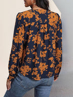Back view of a person wearing the Navy and Orange Print Pull Over Blouse, a long-sleeved navy blue fall top with a repeating orange floral print.
