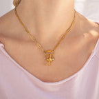 WJW's 18K Gold PVD Paperclip Carabiner Necklace, shown styled with three delicate gold and rhinestone charms and worn by a person in a light pink top, is a customizable piece that lets you elegantly display your favorite charms—perfect for adding sparkle to any outfit.
