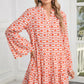 A woman indoors near a window and door wears the Shewin Orange Floral Button V Neck Bell Sleeve Mini Dress.