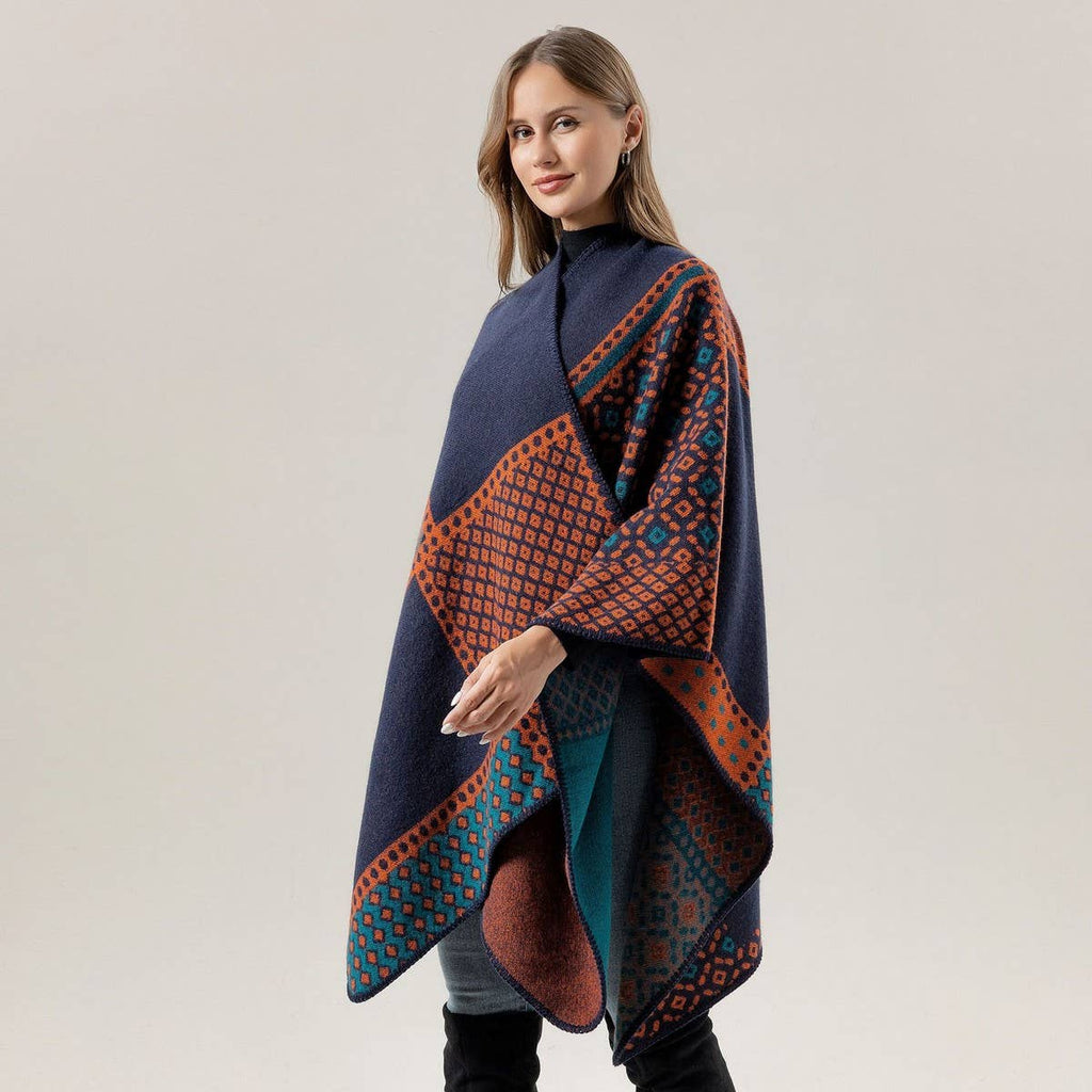 A woman is wearing the ACCITY SHAWL SCARF FAUX CASHMERE SLIT CAPE in a navy blue and orange pattern, styled as a blanket scarf, standing against a plain light gray background.