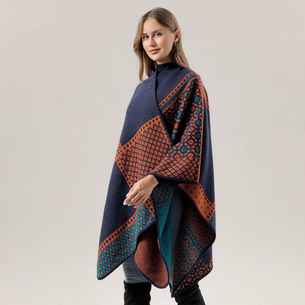 A woman is wearing the ACCITY SHAWL SCARF FAUX CASHMERE SLIT CAPE in a navy blue and orange pattern, styled as a blanket scarf, standing against a plain light gray background.