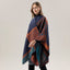 A woman is wearing the ACCITY SHAWL SCARF FAUX CASHMERE SLIT CAPE in a navy blue and orange pattern, styled as a blanket scarf, standing against a plain light gray background.