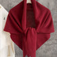 A JC Sunny Fashion Cashmere-Blend Knit Triangle Shawl with a cross-front design in deep red is draped over a hanger against a gray textured wall, next to a white shirt hanging on the left.