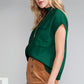 A woman with long blonde hair stands against a plain backdrop, wearing Shewin's Patch Pocket Ribbed Knit Short Sleeve Sweater in green and a brown skirt, offering versatile style perfect for changing weather.