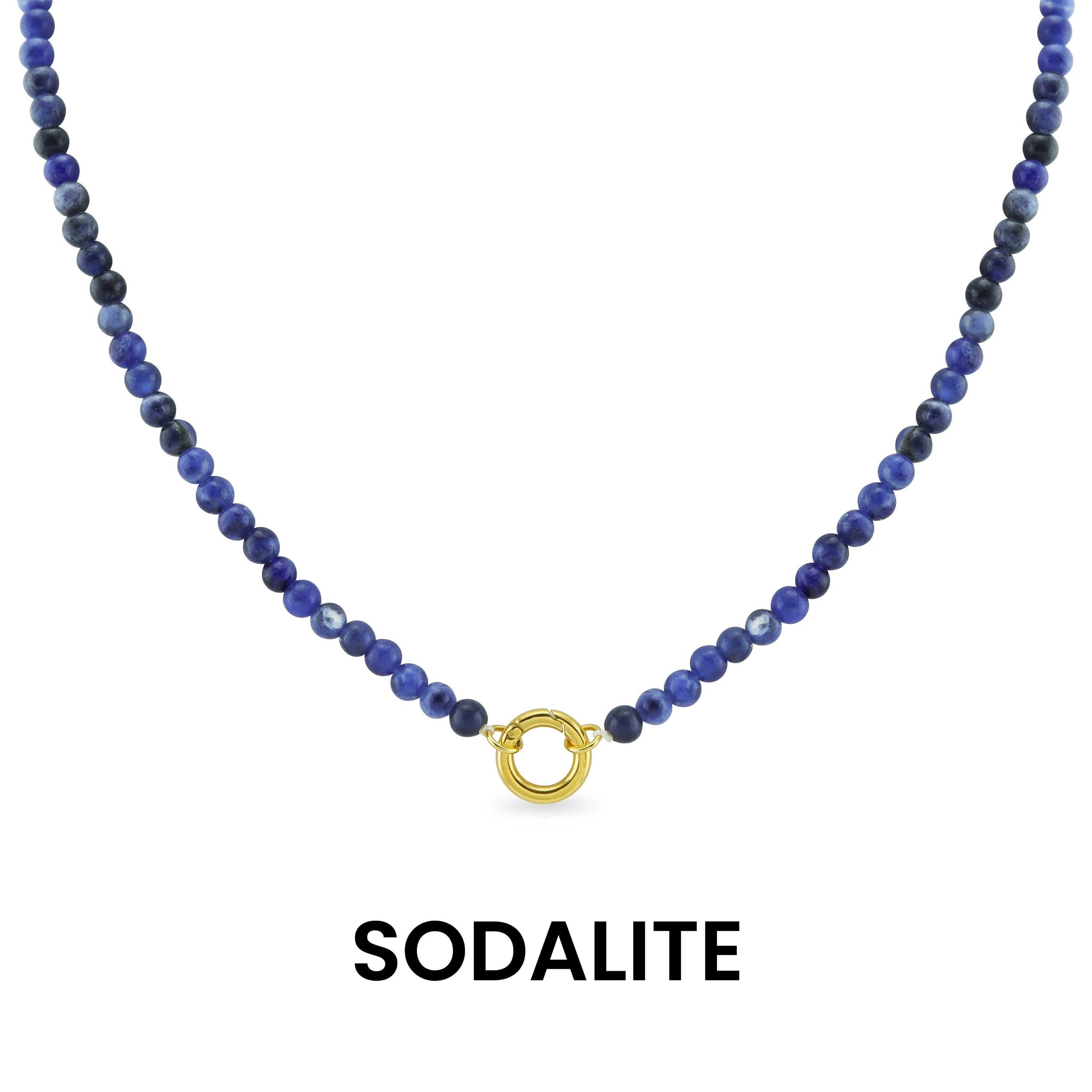 A Semi Precious Natural Stone Charm Keeper Necklace by WJW, featuring round blue sodalite beads and a central 18K Gold PVD Coated clasp, is displayed against a white background. Below the necklace, the word "SODALITE" appears.