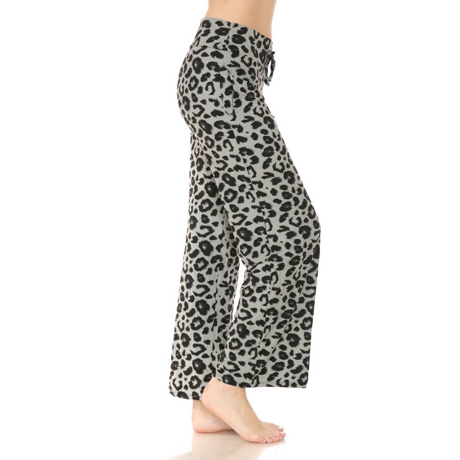 A person stands barefoot, wearing Leggings Depot Buttery Soft Print PJ Pants—loose-fitting, high-rise pajamas with a black leopard print pattern.