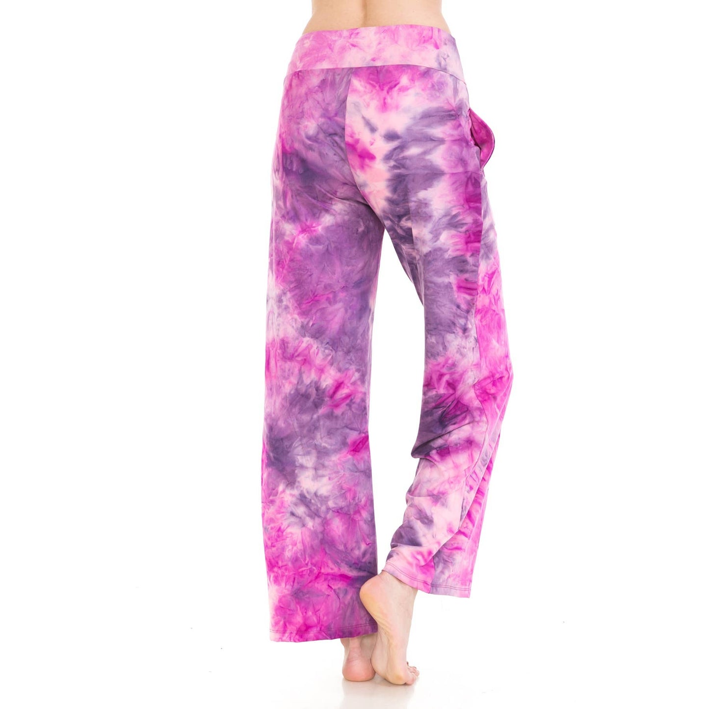 A person stands barefoot against a white background, shown from the back, wearing Leggings Depot Buttery Soft Print Pajama Pants—loose-fitting with pockets in a purple and pink tie-dye design.