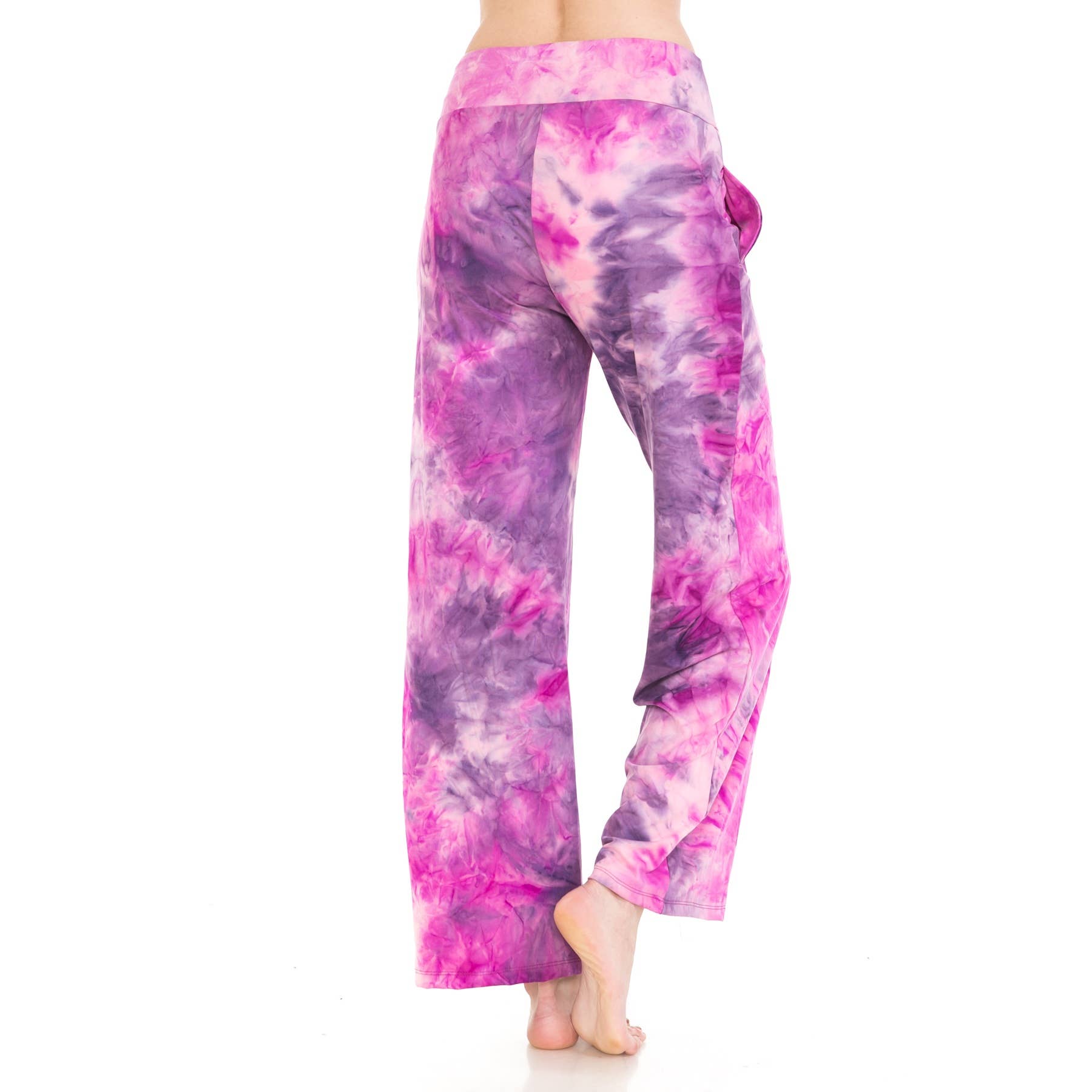 A person stands barefoot against a white background, shown from the back, wearing Leggings Depot Buttery Soft Print Pajama Pants—loose-fitting with pockets in a purple and pink tie-dye design.
