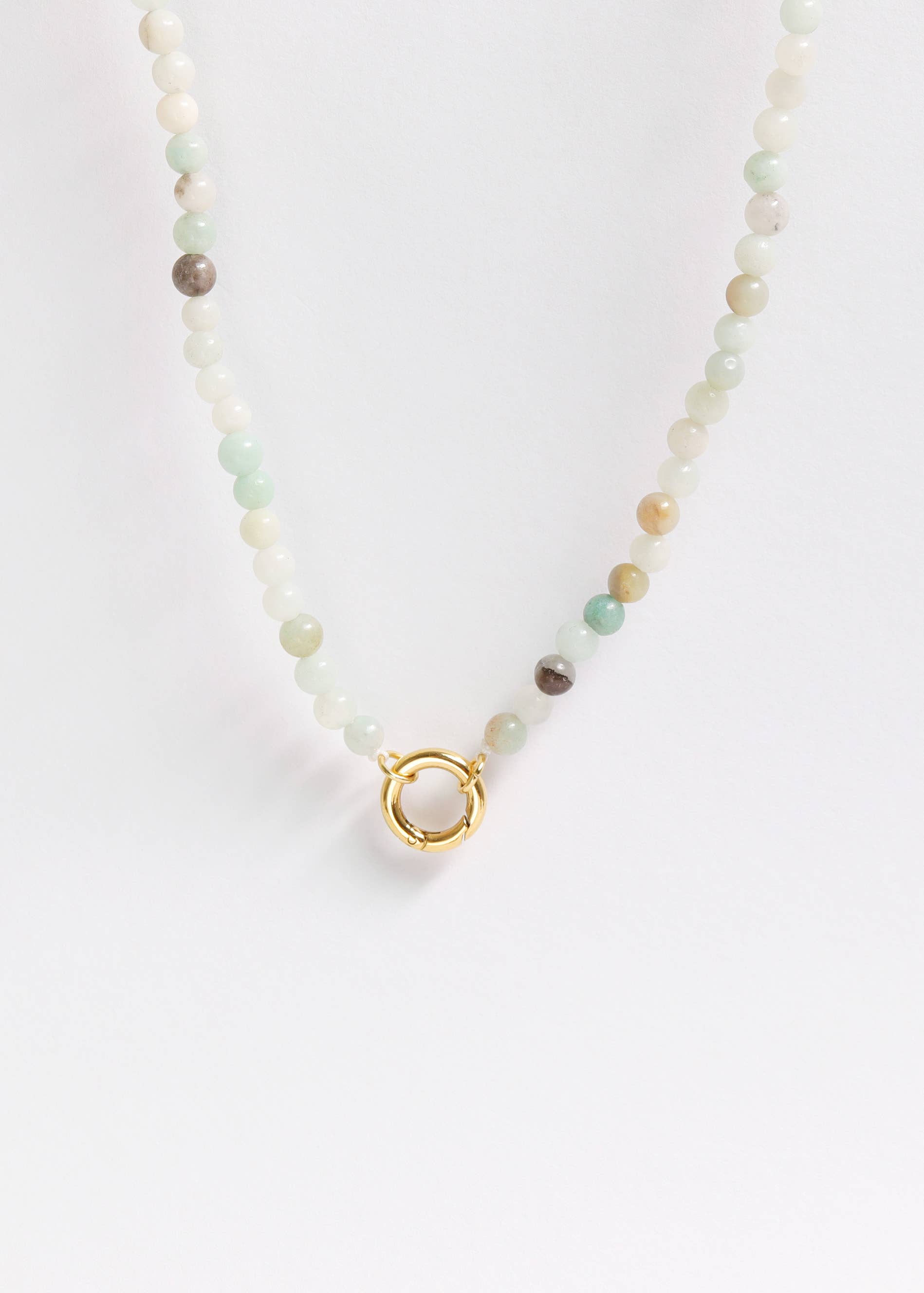 The WJW Semi Precious Natural Stone Charm Keeper Necklace showcases round, light-toned semi-precious stones and is accented by a central circular clasp with an 18K Gold PVD coating, elegantly displayed against a plain white background.