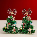 Adorn your holiday look with the Tinsel Christmas Tree Drop Earrings by Lilla Haven—festive ornament charm earrings shaped like Christmas trees and beautifully embellished with red bows, candy canes, gingerbread men, snowflakes, and colorful beads. Set against a cheerful red and beige backdrop, these earrings are the perfect sparkling accessory for any festive ensemble.