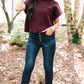 A woman poses outdoors in a Patch Pocket Ribbed Knit Short Sleeve Sweater by Shewin, paired with jeans, a beige hat, and white boots, highlighting her casual style for transitional weather.