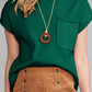 A person wearing a Shewin pink patch pocket ribbed knit short sleeve sweater, styled with a wooden pendant necklace and paired with a brown button-up skirt.