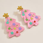 Add a festive touch to your holiday look with the Glittery Christmas Tree Drop Earrings from Lilla Haven—these acrylic statement earrings feature pink Christmas trees topped with shimmering gold stars and adorned with pastel star shapes, pearls, and colorful gem accents, beautifully displayed on a plain light background.