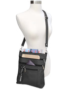 The Roma Leathers, Inc. Cowhide leather crossbody is shown on a mannequin, featuring adjustable shoulder strap and multiple zippered pockets that hold a magazine, wallet, glasses, and pens.