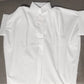 The White Relaxed Short Sleeve Blouse by Rosa Clothing exudes chic style, shown here with its tag attached and laid flat on a grey fabric surface.