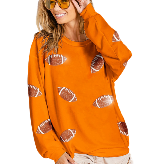 A woman in sunglasses smiling, wearing a FASHION GO Sequin Football Sweatshirt in Orange with sequin details.