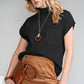 Embracing transitional weather with chic elegance, the woman wears Shewin's Patch Pocket Ribbed Knit Short Sleeve Sweater in black and a tan knit skirt, stylish sunglasses, and holds a brown clutch.