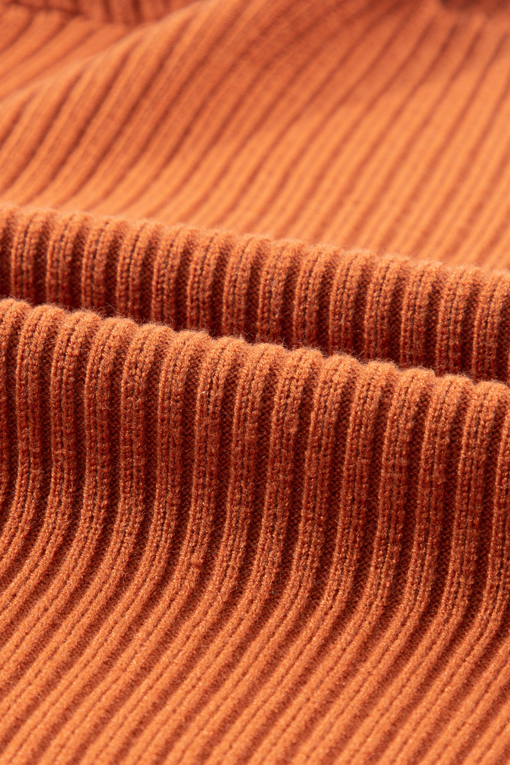 A close-up of the Shewin Patch Pocket Ribbed Knit Short Sleeve Sweater shows its rust-colored fabric with a soft texture and evenly spaced vertical lines, ideal for transitional weather.