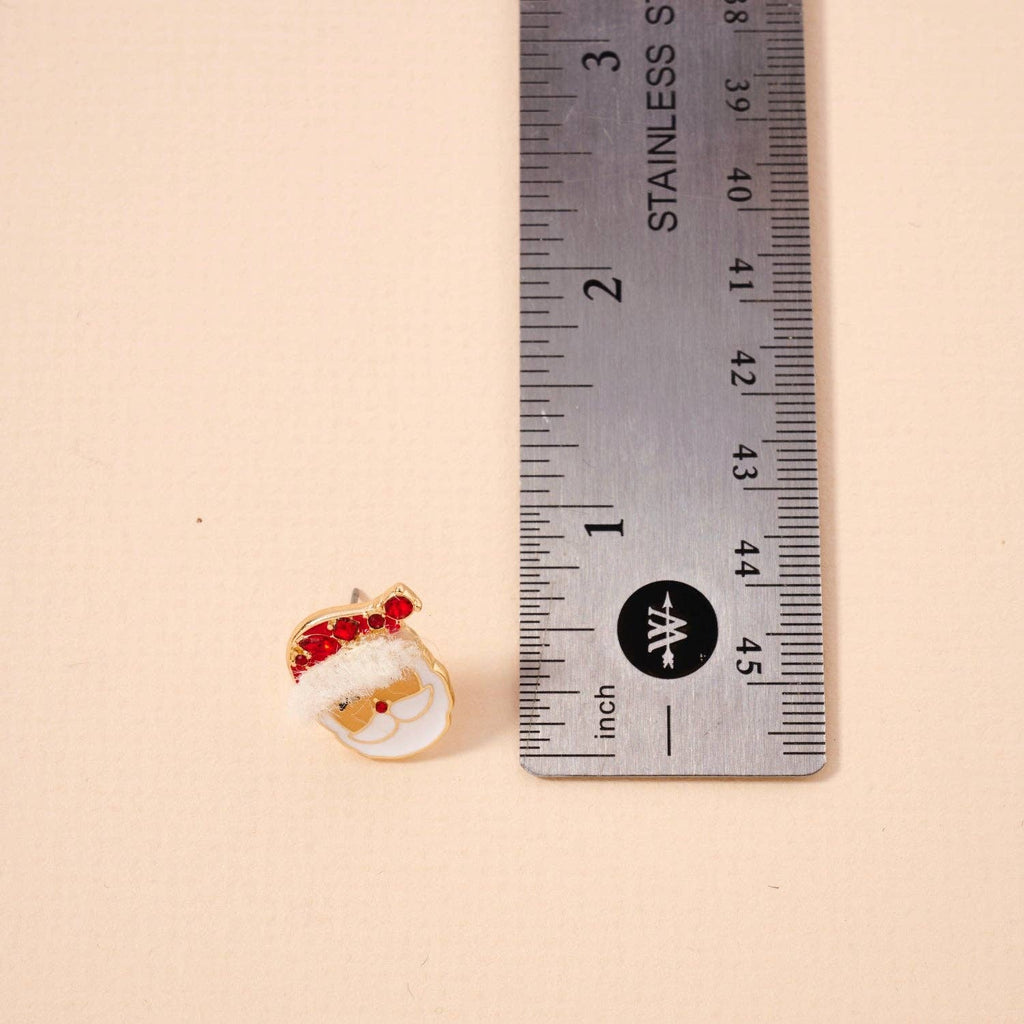 A small Santa Claus pin with red accents is placed next to a stainless steel ruler, showing its size at about 1 inch tall—perfect for pairing with the Lilla Haven Santa Claus Stud Earrings | Red Rhinestone Christmas Earrings or other festive holiday jewelry.