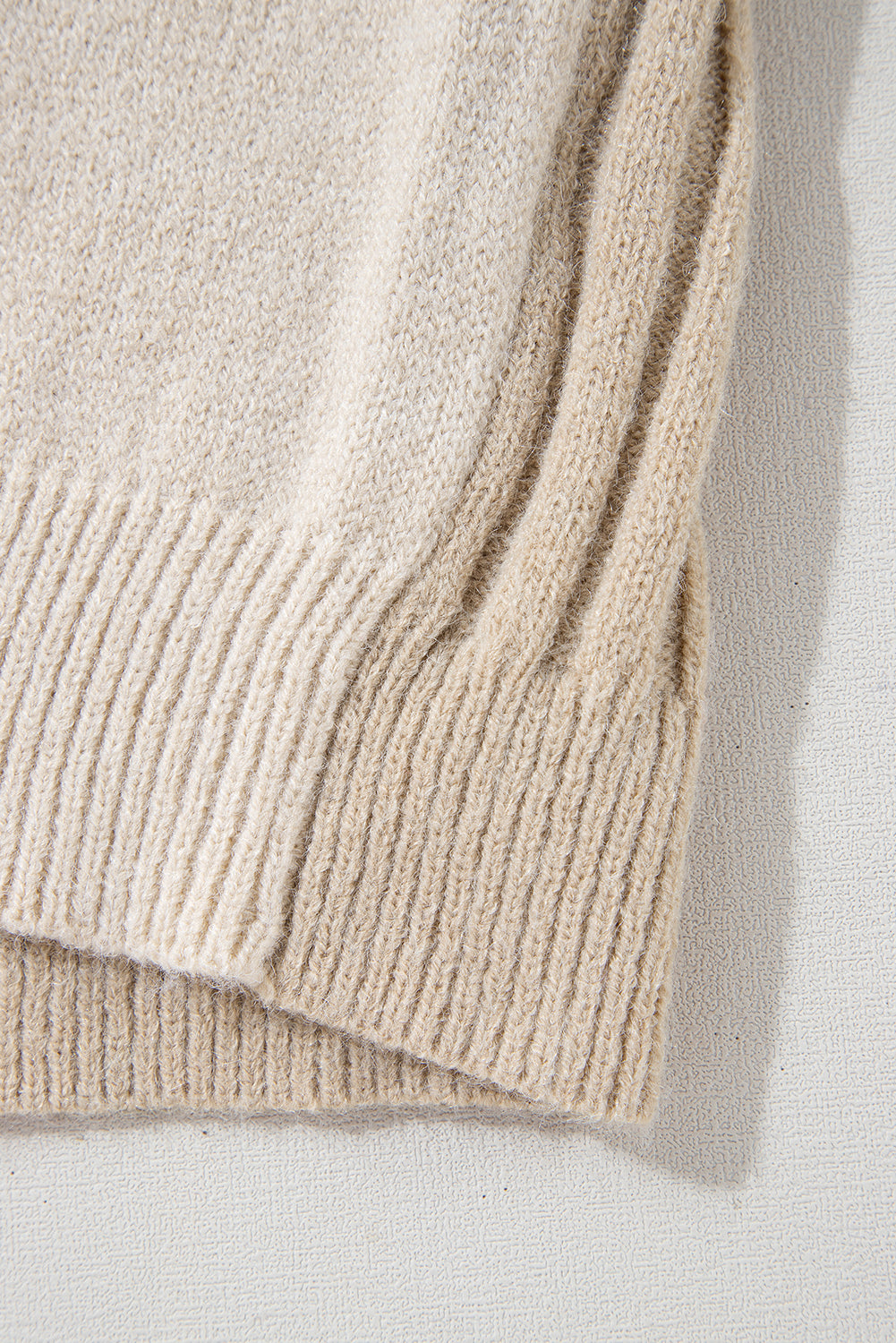 Close-up of the Shewin Khaki Cable Knit Colorblock Crew Neck Drop Shoulder Sweater, showcasing its rib-knit details and relaxed silhouette on a light surface.