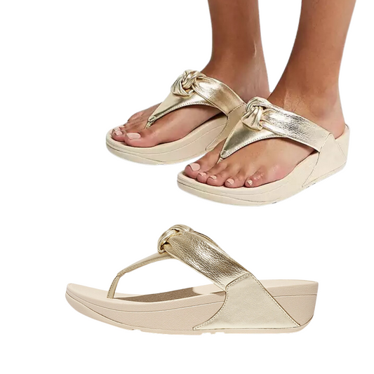 A pair of Lulu Padded Knot Flip Flop in Platino by FITFLOP USA LLC in gold metallic with cushioned, ergonomic design and knot detail, shown both being worn and as a standalone item against a white background.