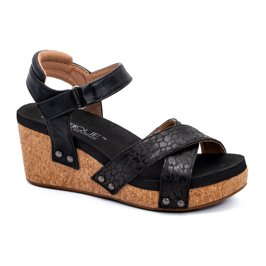 CORKY'S FOOTWEAR INC Kindle black wedge sandal with a cork heel, featuring a crisscross front strap, ankle buckle, and studded details.