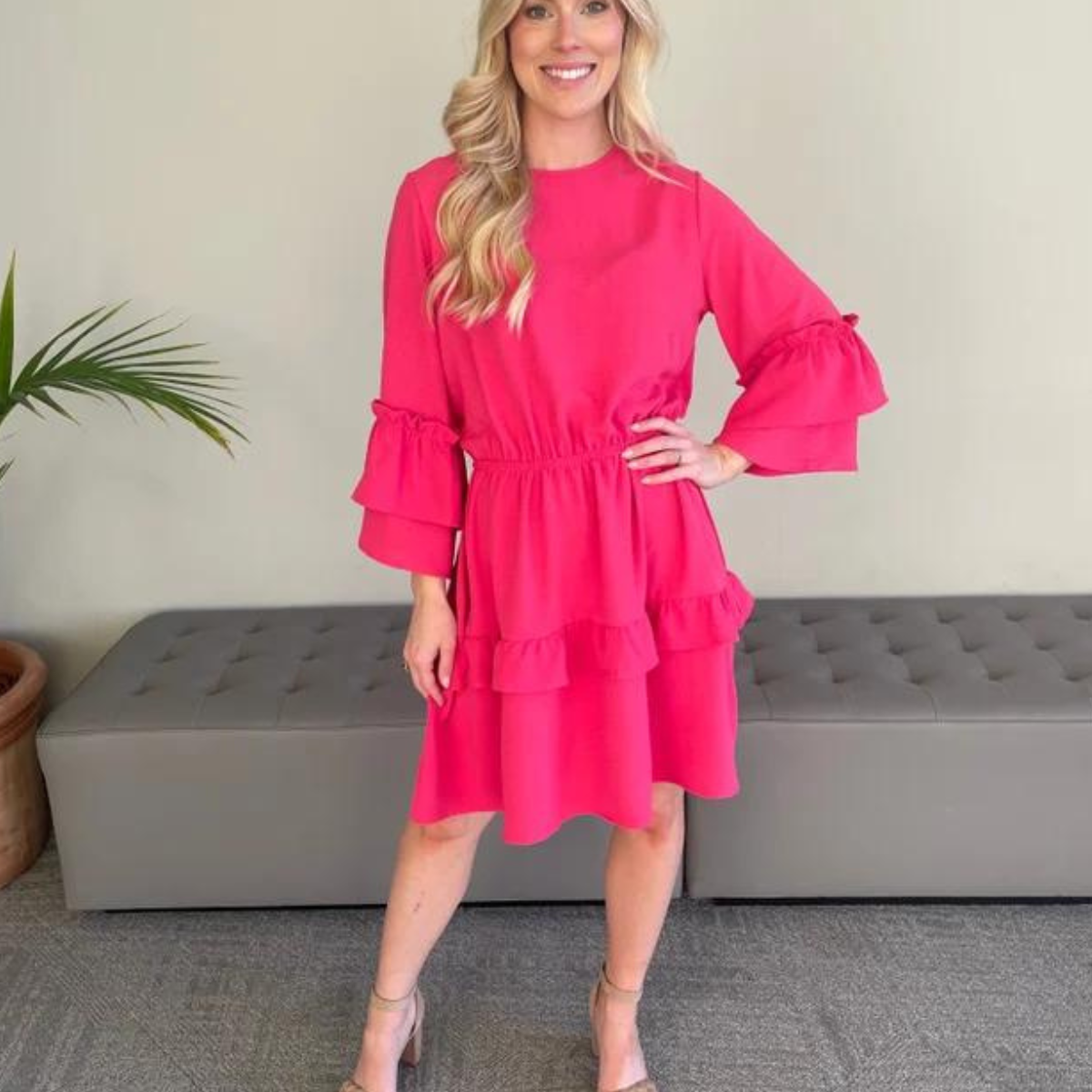 A blonde woman in a Pink Ruffle Accent Dress by Carole Christian, featuring a luxor polyester fabric, is posing for a photo.