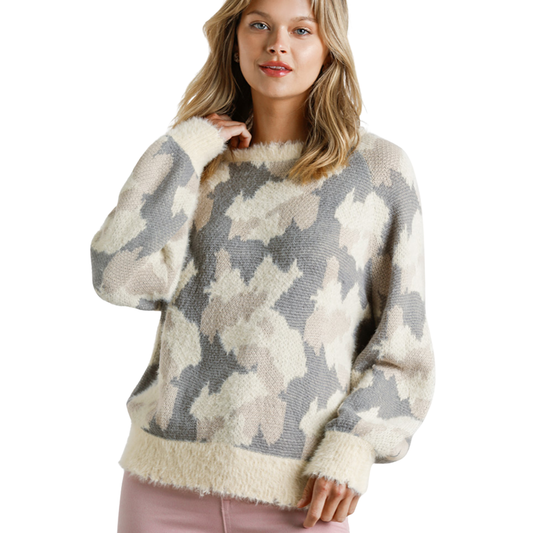 A woman wears the Umgee Cream mix Print Sweater, featuring an abstract beige, gray, and cream pattern, paired with light pink pants, standing against a white background.