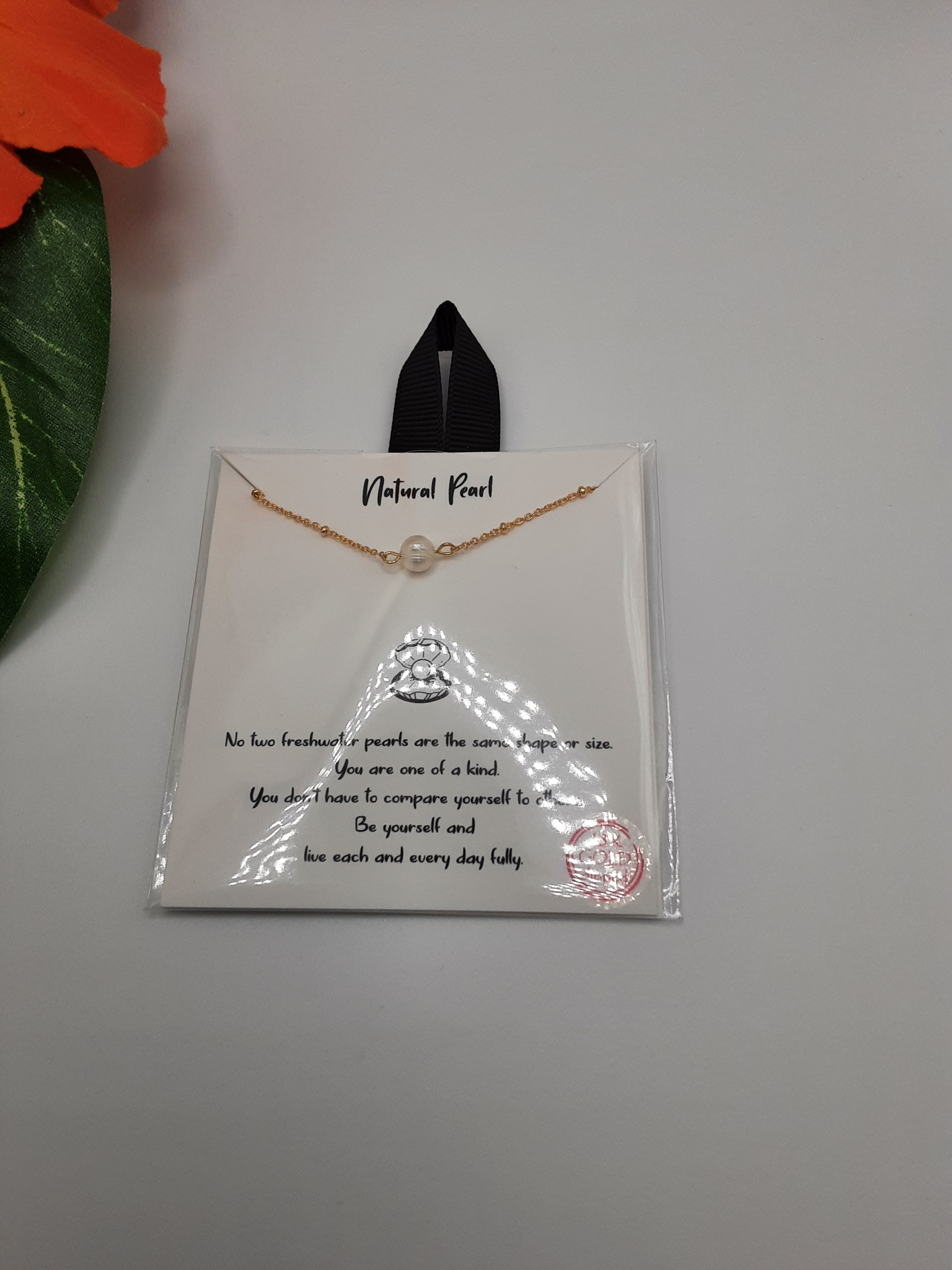 A Natural Pearl 16 inch Carded Necklace by SPECIAL EFFECTS is showcased in clear plastic packaging. The package features a message celebrating individuality and uniqueness, with a green leaf and part of an orange flower visible. Main image