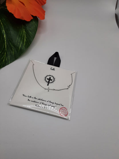 A Faith Small Crosses on Chain Necklace Gold dipped by SPECIAL EFFECTS, paired with a card inscribed with "Faith" and a Bible quote, elegantly packaged in a clear plastic sleeve adorned with a "handcrafted" sticker. An orange flower is visible in the background.