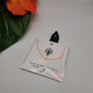 The Faith Small Crosses on Chain Necklace Gold dipped by SPECIAL EFFECTS is displayed on a white card, adorned with a black ribbon and script text. Nearby, an orange flower with green leaves adds a touch of color.