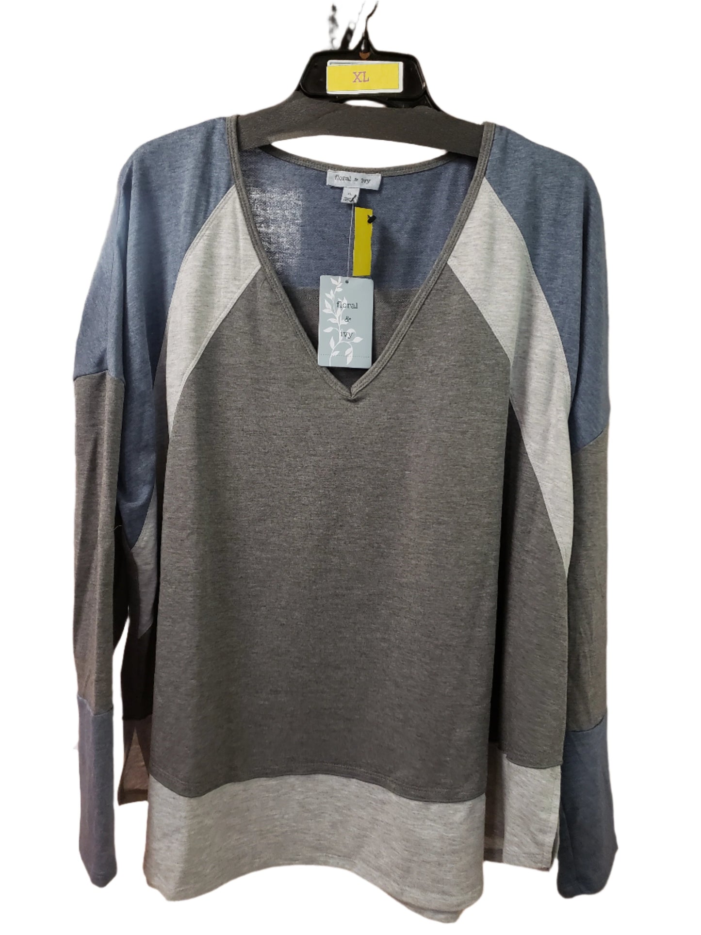 A lightweight, long-sleeve V-neck tunic crafted by Ronnie Salloway & Co Inc features stylish blue and gray color blocks in a knit design. It hangs on a rack with a yellow XL size marker, surrounded by an array of diverse clothing items.