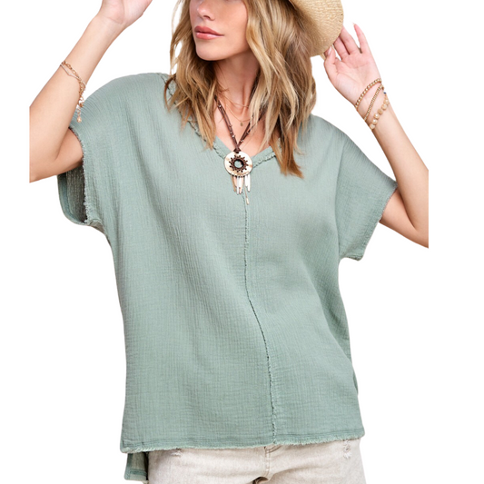 Woman posing in a light green Loose Fit Gauze Short Sleeve Top from FASHION GO with raw edge details and accessories, including a sun hat, against a white background.