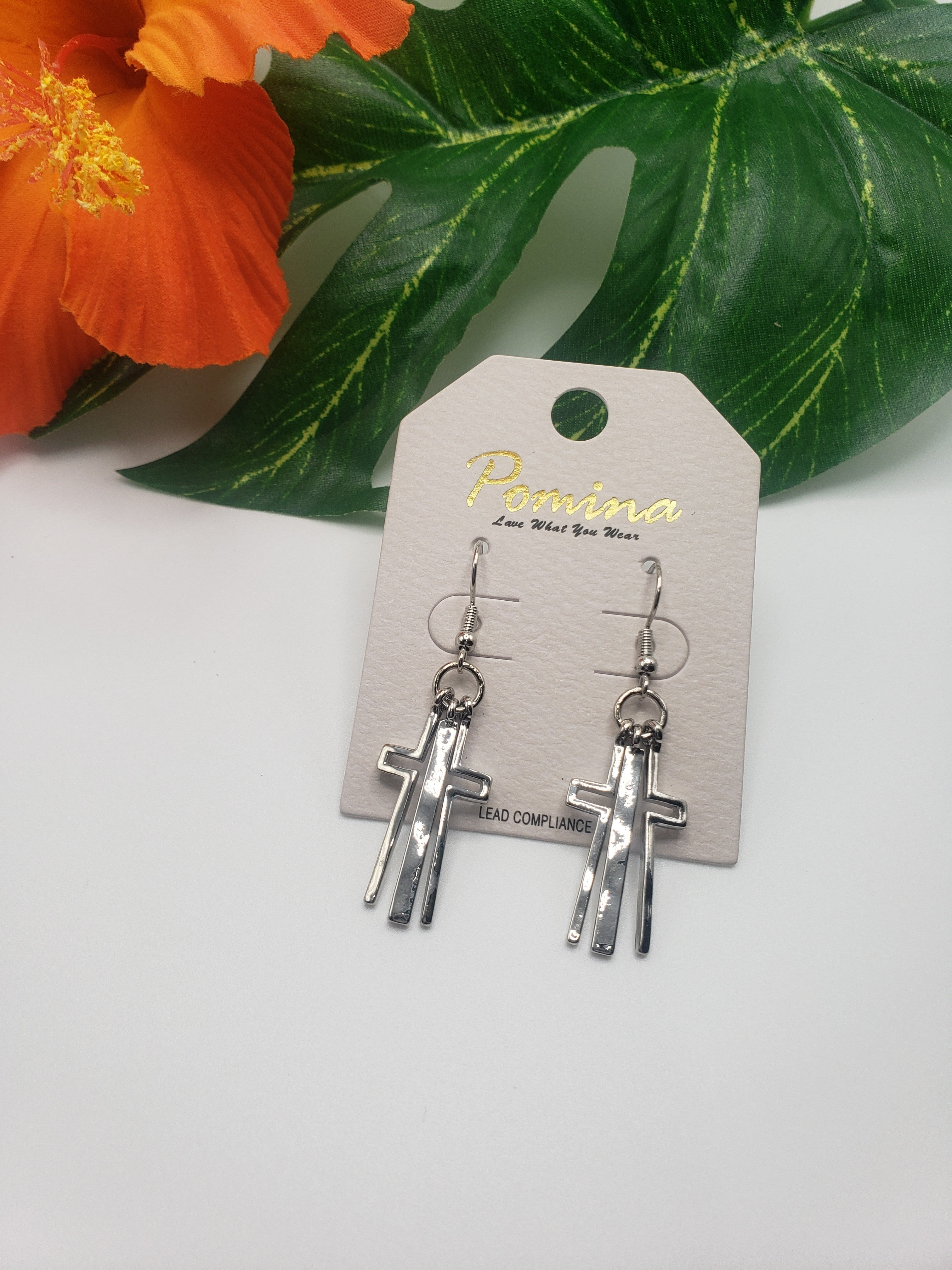 A pair of Fashion Go silver CROSS EARRINGS with a flower in the background. Main image