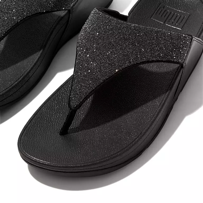 A pair of FIT FLOP OPUL black sandals with glittery straps suitable for dressier occasions and featuring a FITFLOP USA LLC sole, positioned on a white surface.