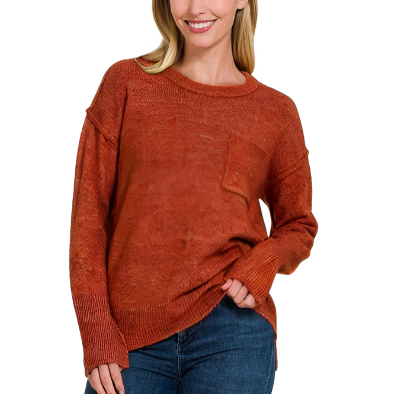 A woman smiling with her hands in her pockets, wearing a Zenana MELANGE HI-LOW HEM SWEATER in dk rust.