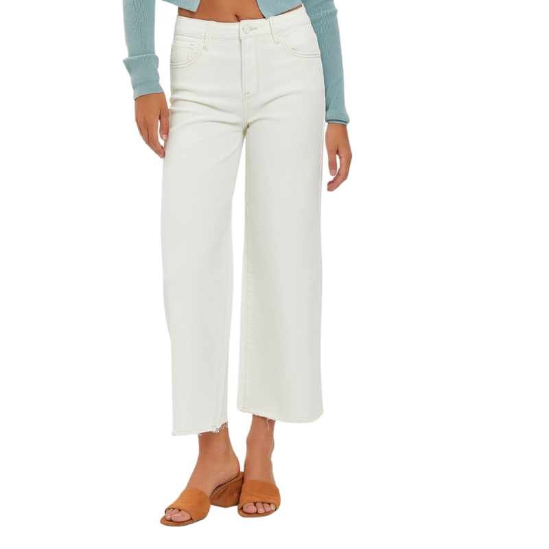 A woman wearing RISEN HIGH RISE TUMMY CONTROL CROP WIDE LEG - cream pants with frayed hem and a blue sweater.